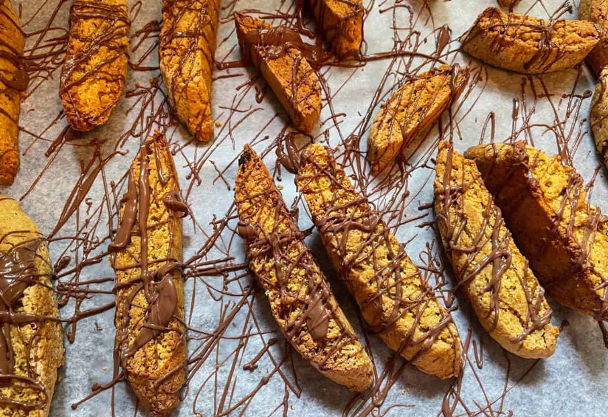 A tray of pumpkin biscotti with chocolate drizzle on them.