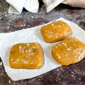 Three squares of caramel are sitting on a piece of paper.