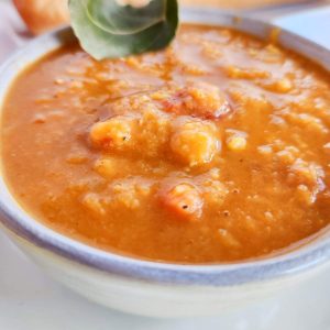A bowl of carrot and red lentil soup with sage.