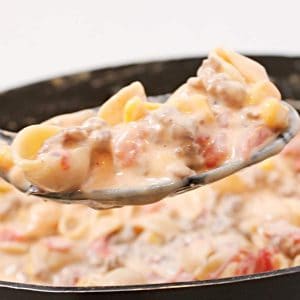 A spoonful of pasta and meat in a skillet.