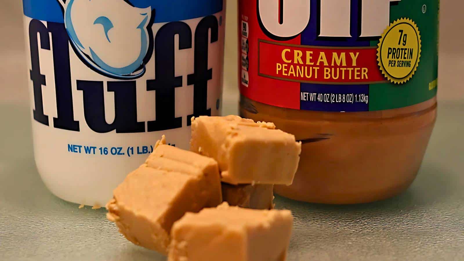 Three pieces of peanut butter fudge in front of marshmallow fluff and peanut butter jars.