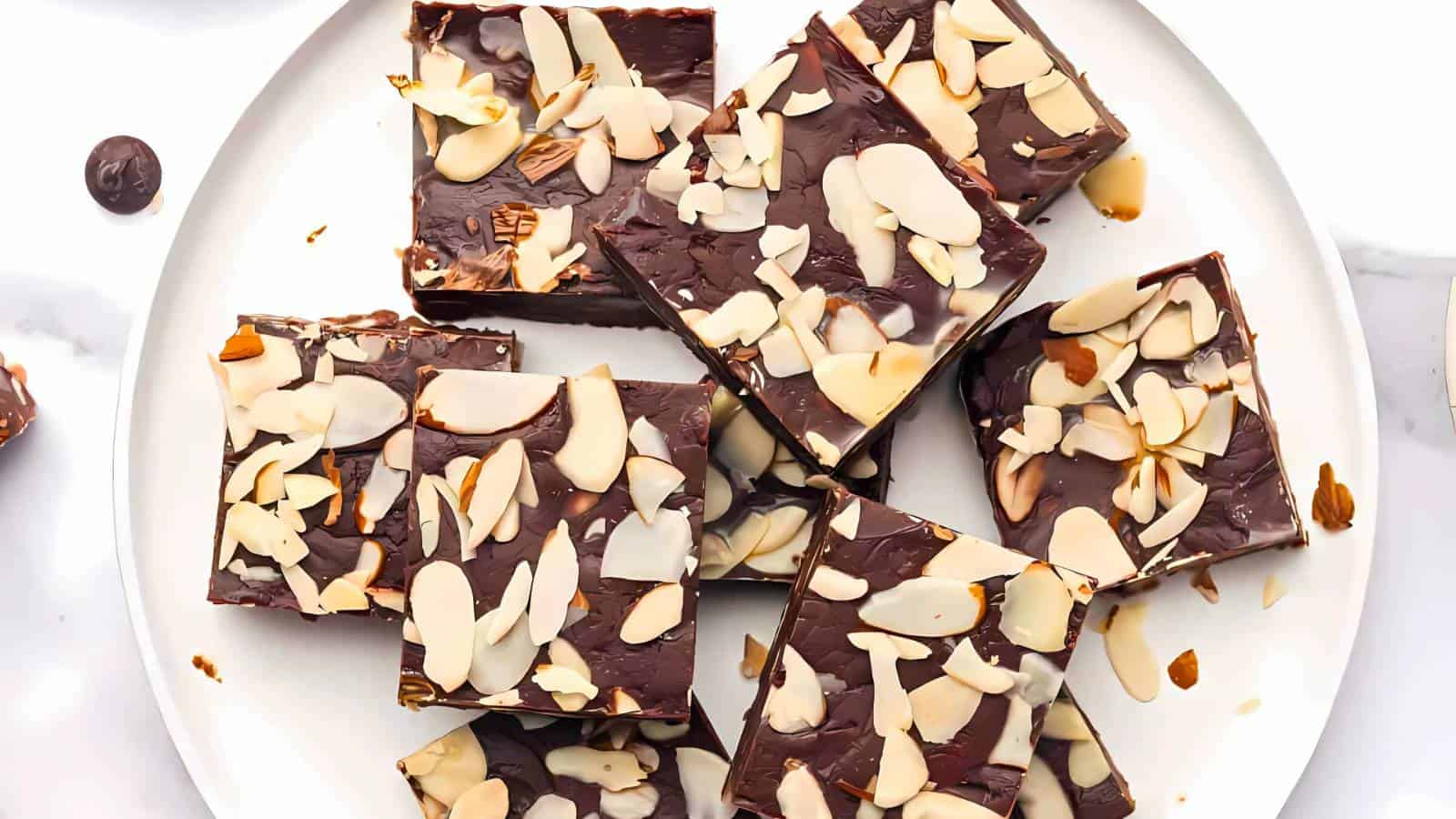 A plate of chocolate fudge squares topped with almond slices.