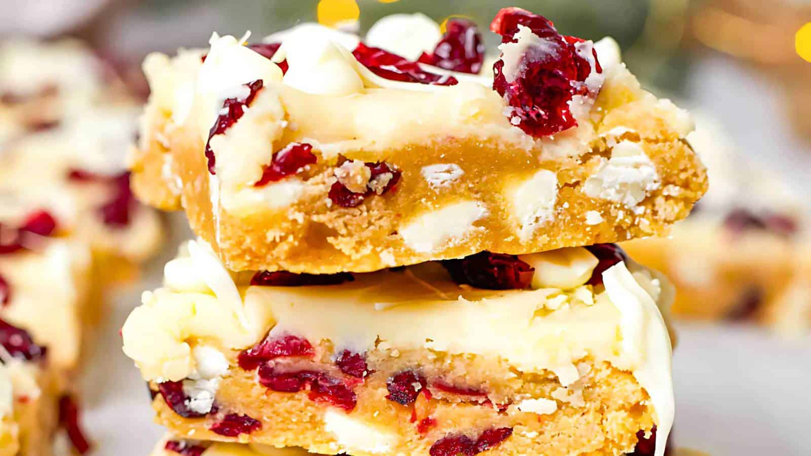 Two stacked dessert bars with white chocolate, cranberries, and a light brown base.