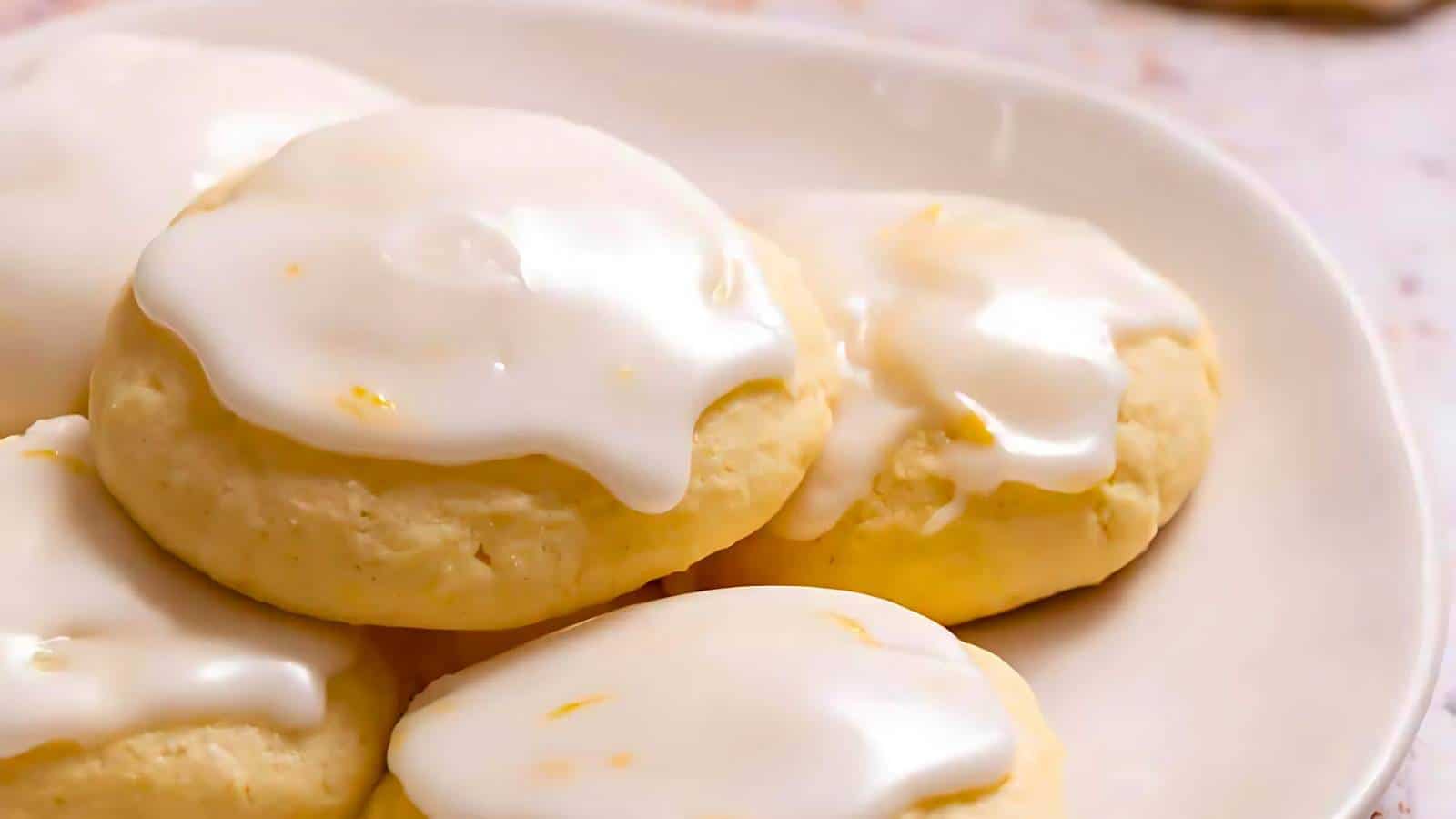A plate of round, soft cookies topped with a smooth layer of white icing.
