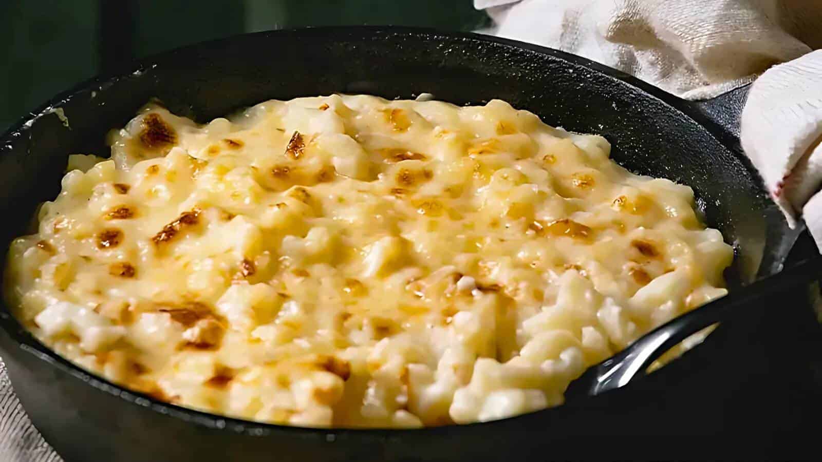 A skillet filled with freshly baked mac and cheese, with a golden, bubbly cheese crust on top.