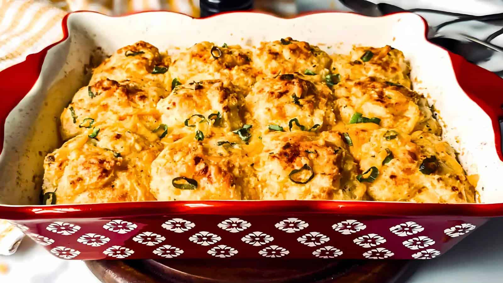 Baked meatballs in a red and white patterned dish, topped with sliced green onions.