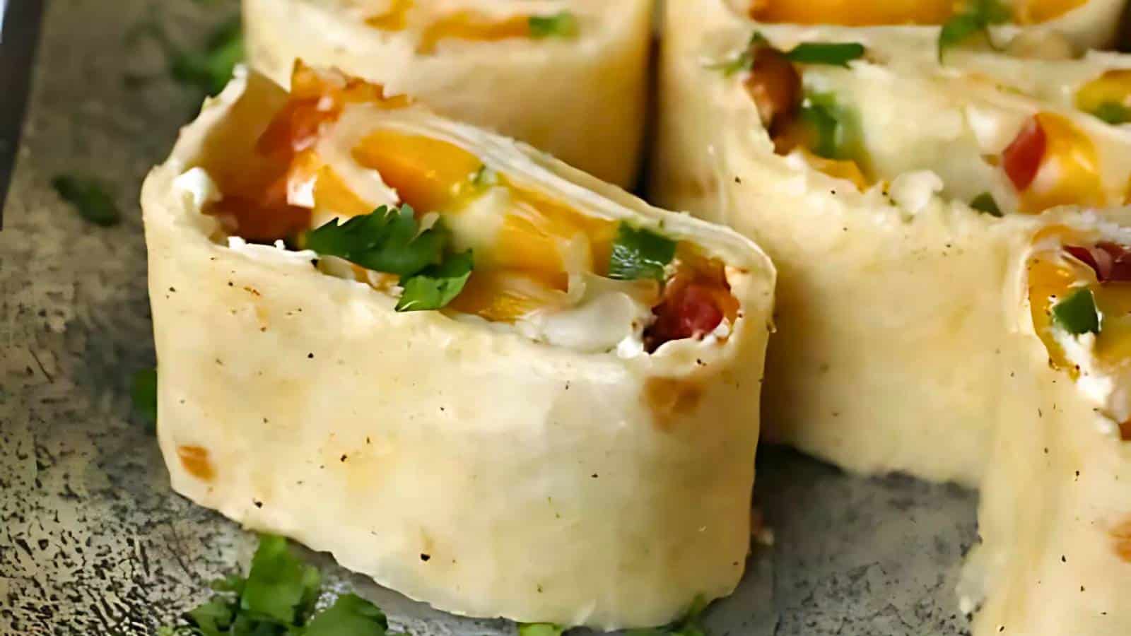 Close-up of tortilla pinwheels filled with cream cheese, diced vegetables, and herbs, garnished with chopped cilantro on a plate.