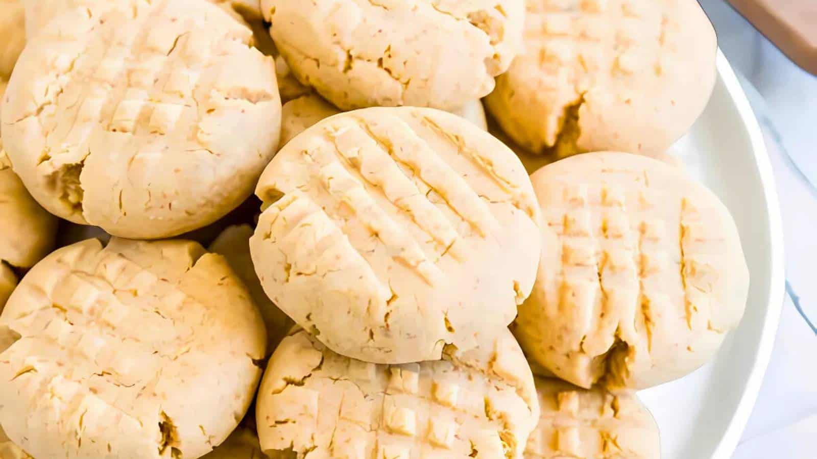 A plate of round, light brown cookies with a crisscross fork pattern on top of each cookie.