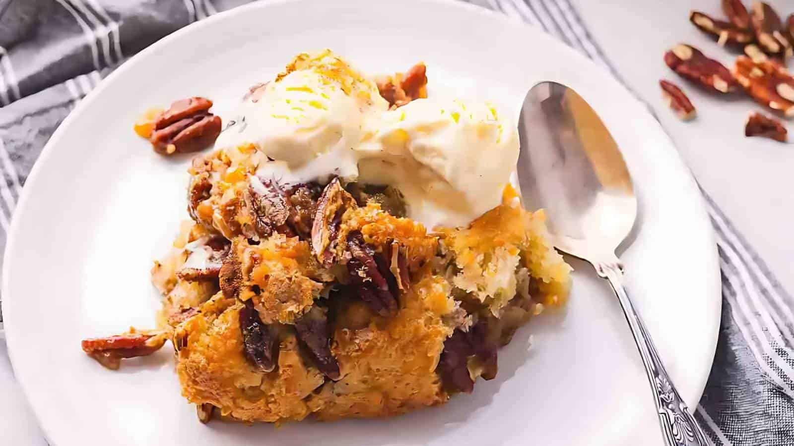 A plate with a serving of pecan-topped dessert, a scoop of vanilla ice cream, and a spoon on the side. Some pecans are scattered in the background.