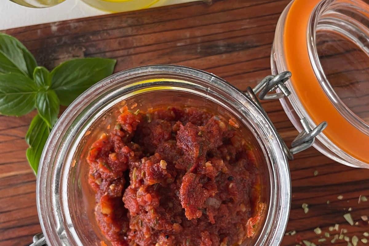 A jar of homemade spicy pizza sauce next to a glass jar of olive oil.