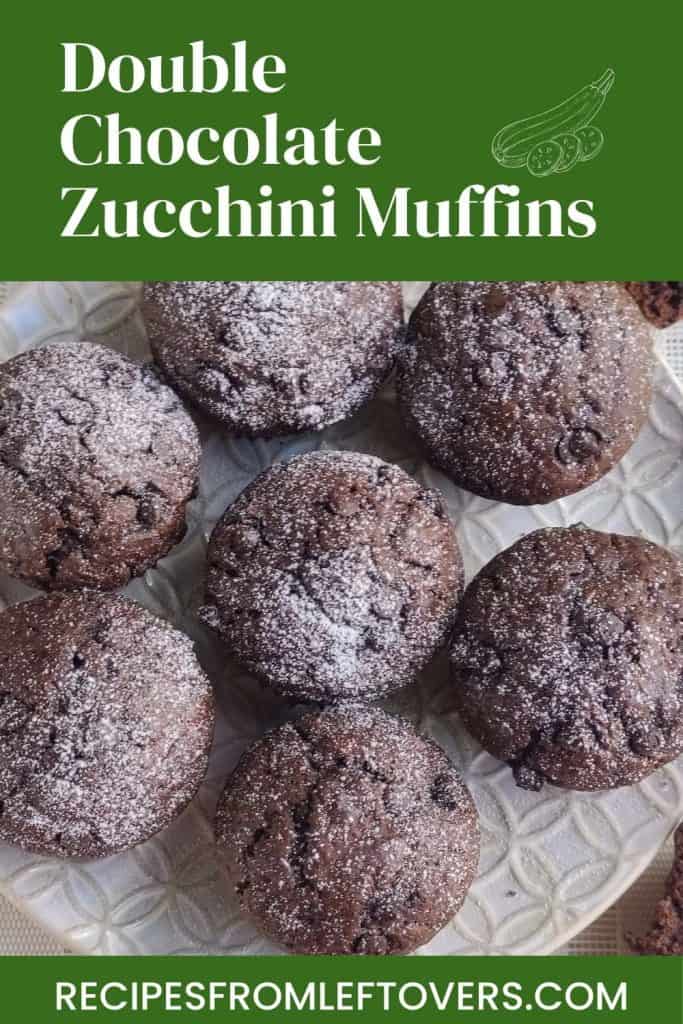 Seven double chocolate zucchini muffins dusted with powdered sugar are arranged on a glass plate. The top text reads “Double Chocolate Zucchini Muffins,” and the bottom text displays “RECIPESFROMLEFTOVERS.COM.”.