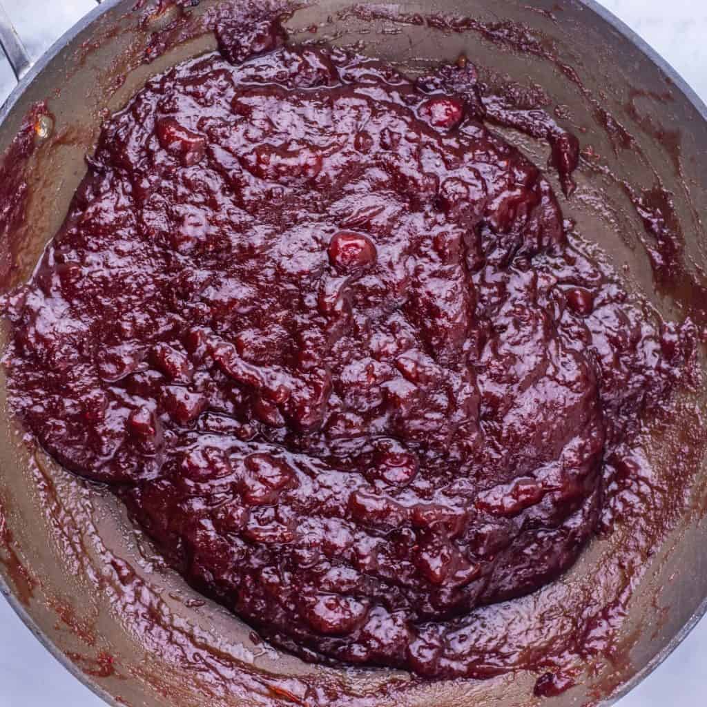 Thick, glossy homemade cranberry sauce with visible chunks of cranberries, perfect as a Cranberry Glaze for Turkey Stuffing Meatballs and beautifully spread in a pan.