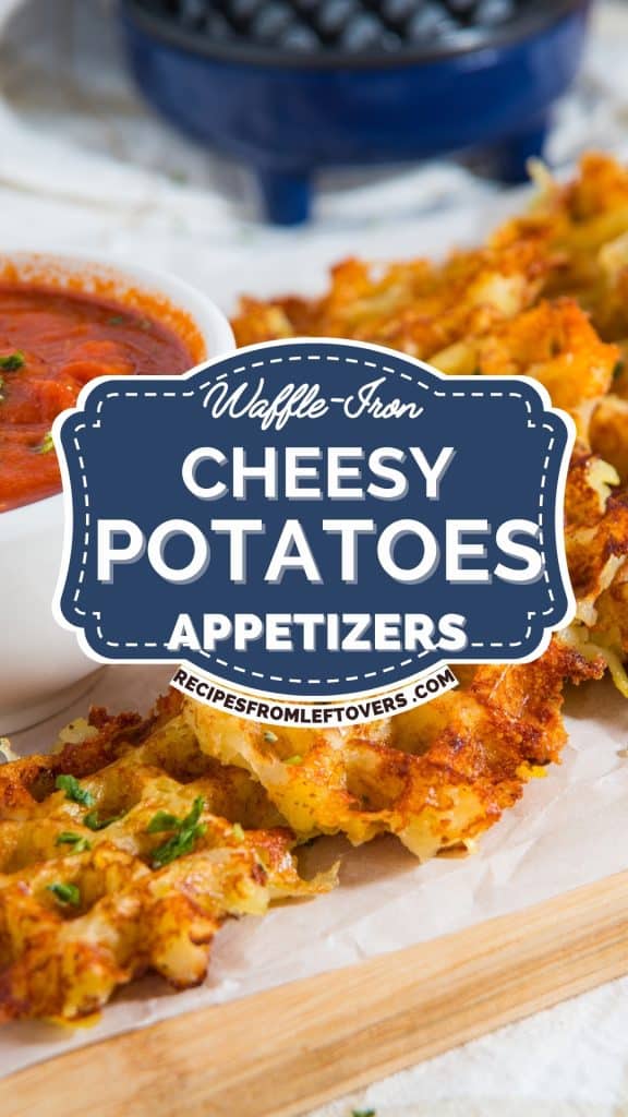 Close-up of crispy waffle iron cheesy potato appetizers served on a wooden tray, with a bowl of red dipping sauce and a dish of blueberries in the background. Text overlay reads, “Waffle Iron Cheesy Potatoes Appetizers.”.